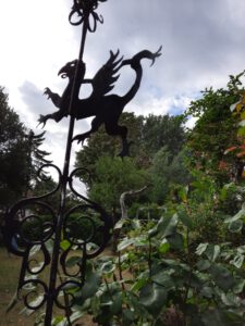 eine Wetterfahne in Form eines Drachens in einem grünen Garten